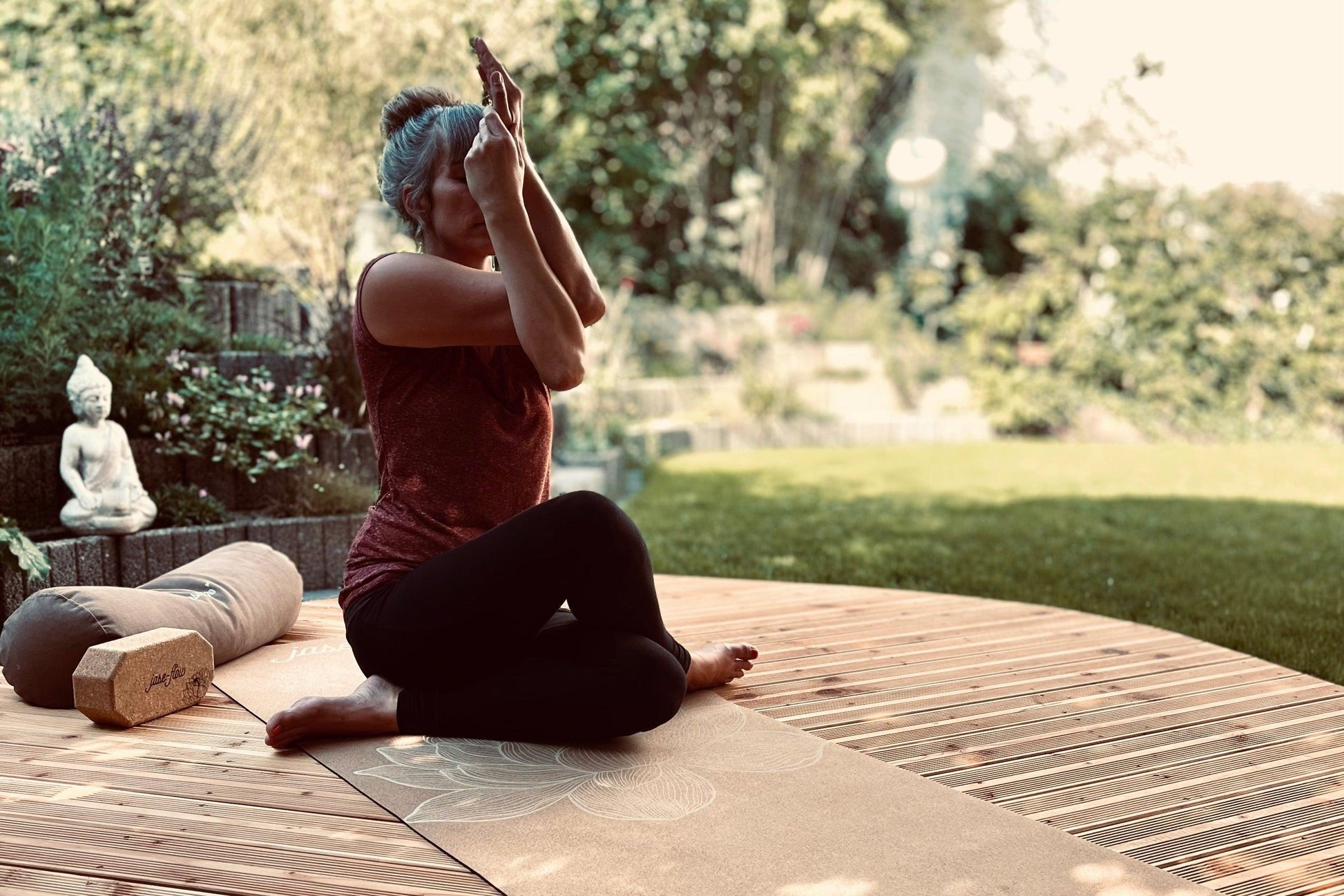 Yin-Yoga Lehrerin Jase mit der  Asana Adlerarme auf der  nachhaltigen Yogamatte Kork Lotus -  mit Yogabolster und Yogablock aus Kork während dem Praktizieren